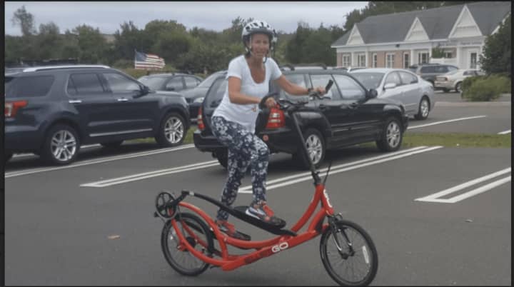 Debi Povinelli, co-owner of the Ridgefield Running Company, riding the elliptiGO bicycle outside her store.