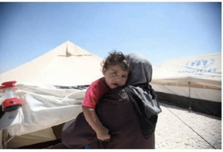 A Syrian refugee woman holding her child.  The Refugee Resettlement Committee of Ridgefield is seeking people interested in helping a refugee family settle in the region.