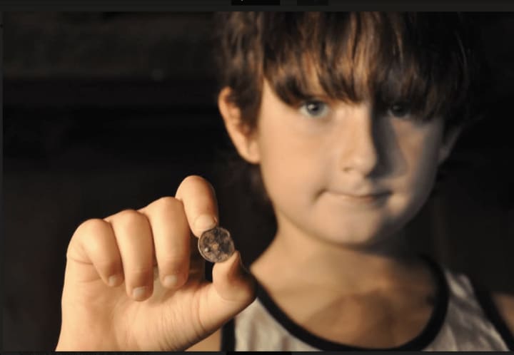 Jake Lattanzi, 8, displays Spanish silver coin (circa 1773-89) he found in Monroe with his dad.