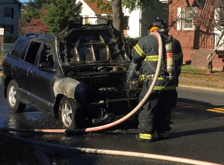 A firefighter hoses off a charred SUV that went up in flames in Maywood Friday.