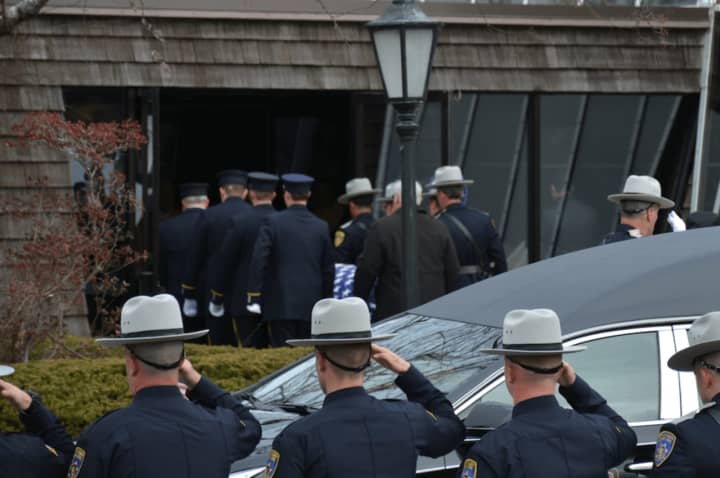Putnam County Sheriff&#x27;s deputies give salutes (in foreground) as as Undersheriff Peter Convery&#x27;s casket is brought inside a Mahopac church for his funeral (pictured in background).