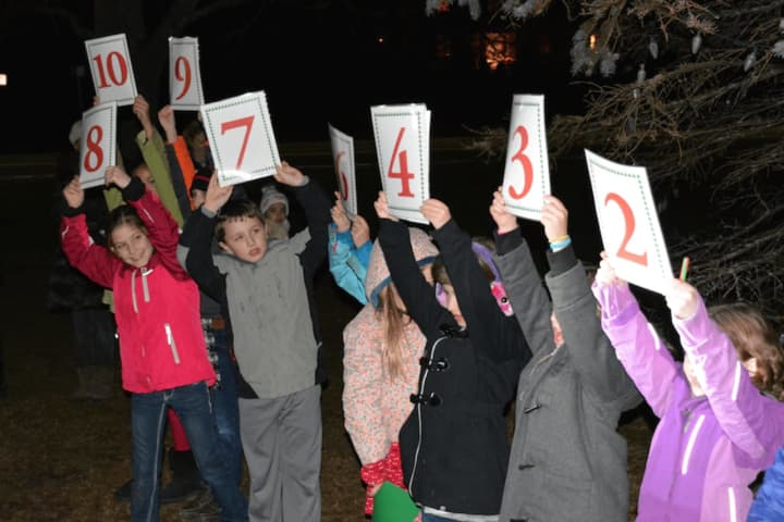 Kids hold up countdown signs for Bedford Village&#x27;s Christmas tree lighting.
