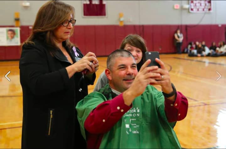 Bethel High School principal Chris Troetti looks at his reflection after he got his head shaved at the event.