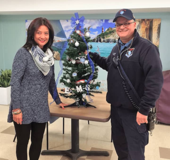 Stamford EMS Paramedic Mike Mansi presents a donated Stamford EMS tree to Minette Zambo of the Cassena Care of Stamford during the third annual Festival of Trees.