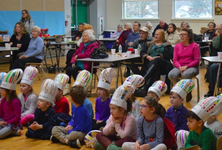 Members of the Bigelow Center for Senior Activities and kindergarteners for Osborn Hill Elementary School listen to the school&#x27;s fifth-grade chorus.