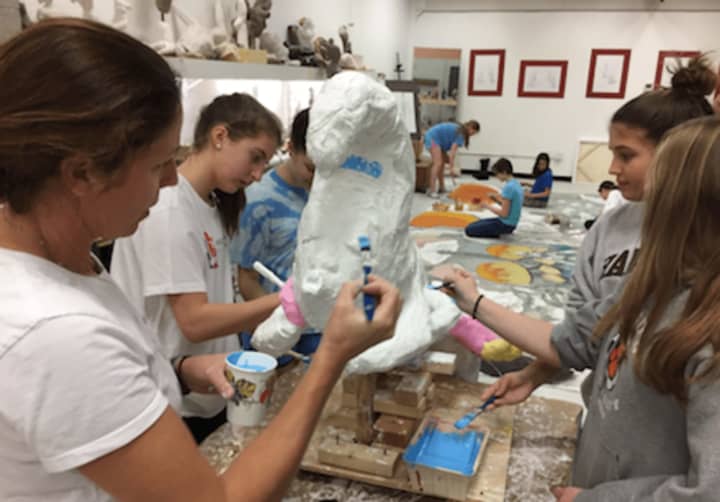 Stamford-based artist Paige Bradley, at left, and Greenwich Country Day students working on the Alice in Wonderland theme set for Kids in Crisis fundraiser.