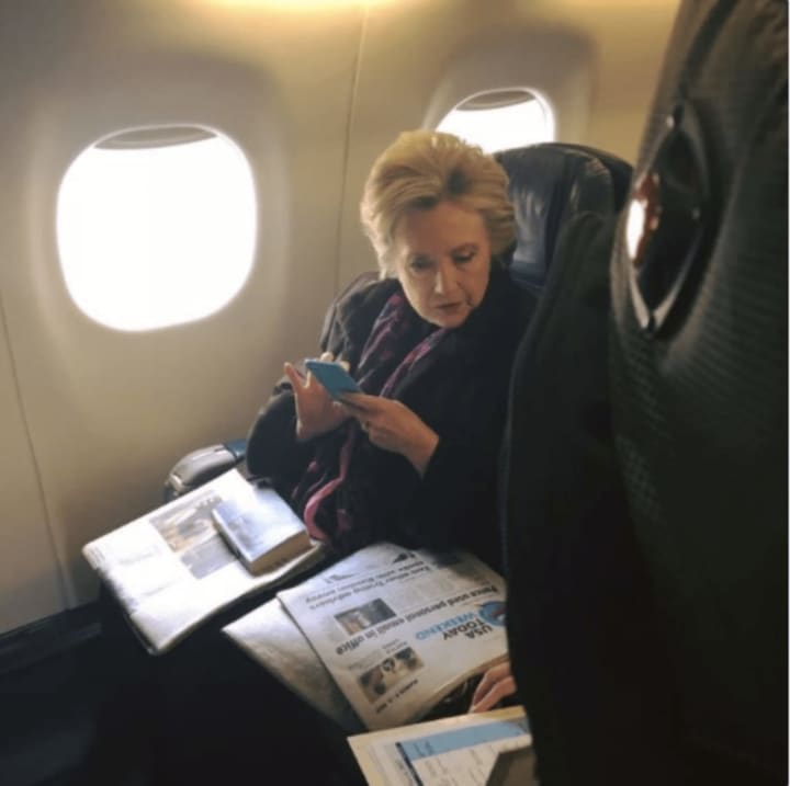 A passenger on a New York City-bound flight from Boston snapped this photo of Hillary Clinton reading a newspaper story about Vice President Mike Pence&#x27;s use of personal email. The passenger posted the photo on Twitter.