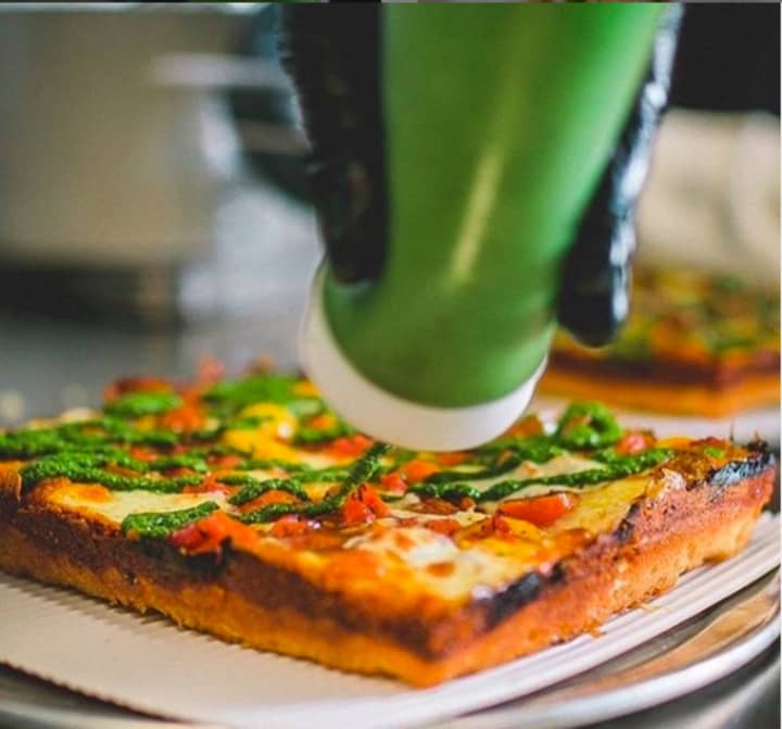Chef Charlie Webb applying the finishing touches to a &quot;PYT&quot; slice, which is topped with heirloom tomato and red pepper relish, mozzarella, basil pesto, parmesan cheese and aged balsamic