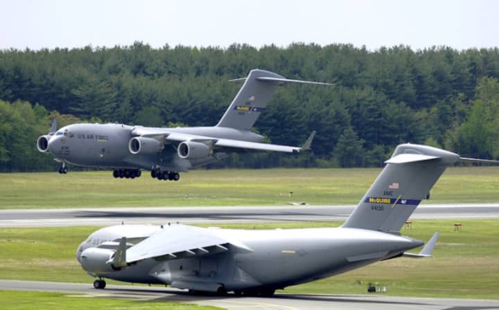 A C-17A Globemaster III from the 305th Air Mobility Wing lands as another C-17A prepares to take off at Joint Air Base McGuire-Dix-Lakehurst in Burlington County,