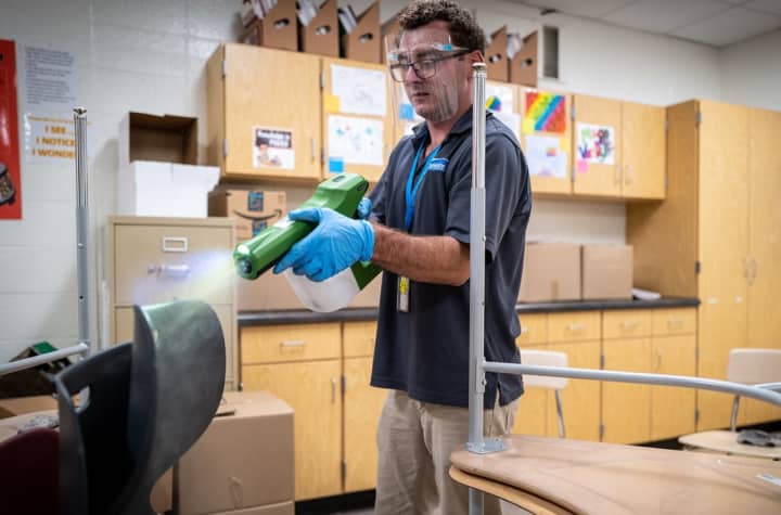 A man sprays disinfectant on school equipment.