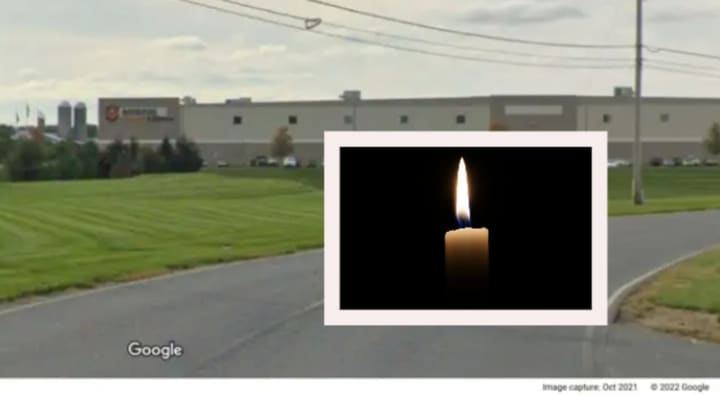 A candle overlaying an image of the Amazon Fulfillment Center in Carlisle.