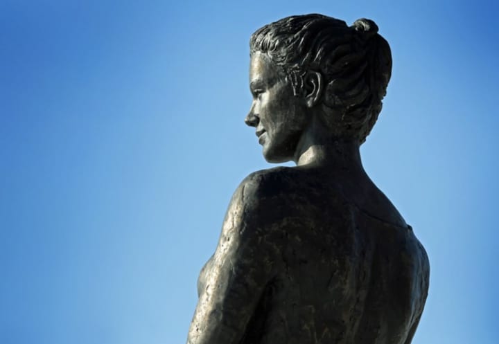 A stock image of a bronze statue of a woman.