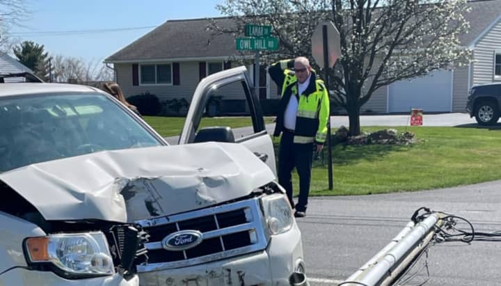 An officer scratching his head while looking at the crash scene.