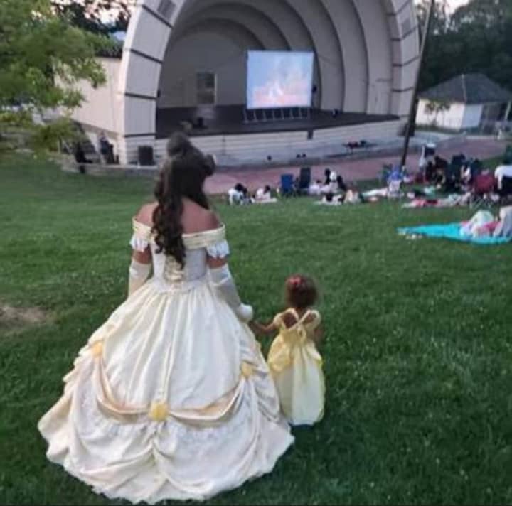 A movie showing at Reservoir Park in Harrisburg as Disney&#x27;s Princess Belle and a little girl watch.