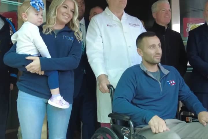 Suffolk County Police officer Michael LaFauci, flanked by his fiance and 17-month-old daughter, is released from Stony Brook University Hospital on Thursday, May 18, one week after being shot while on duty.