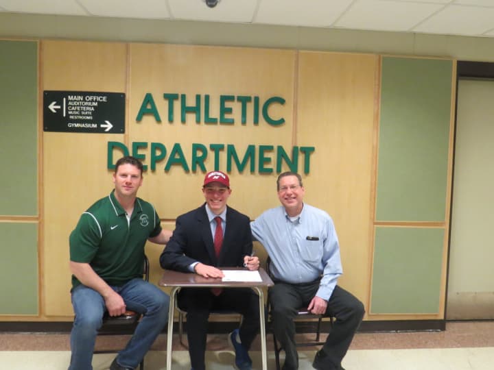Yorktown High School senior Michael Rothman signs his academic scholarship to play baseball at Manhattanville College with his father, Allan, right, and coach Sean Kennedy, left, in attendance.