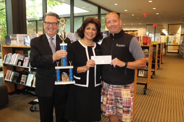 Wilton Library’s executive director Elaine Tai-Lauria receives a generous donation of $1,200 from Mitch Ancona. Holding the trophy is Bocce Brawler Michael Crystal (husband of Janet Crystal, marketing communications manager for the library).
