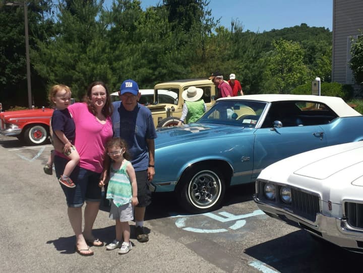 An Atria resident and his family standing with the classic cars on display at the show.