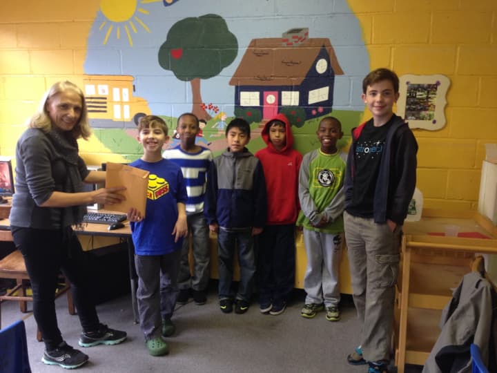 Quinn Taveira, 10, of the Brick Bosses, far left, and Logan Taveira, 14, of the Astromechs, far right, present their collection envelope to Ana Kabashi, school-age program director for the Ossining Children&#x27;s Center. 