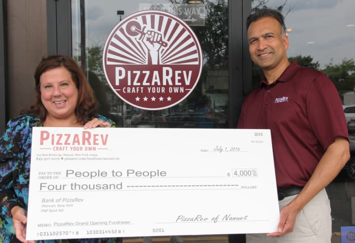 People to People Executive Director Diane Serratore is presented with a check for $4,000 by PizzaRev owner Satyen Shah.
