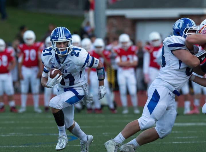 Darien&#x27;s Shelby Grant runs behind a blocker during Saturday&#x27;s win over Greenwich. He set a school record with six touchdowns. 