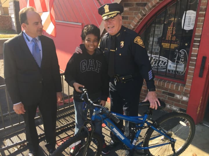 Bridgeport Mayor Joe Ganim, left, and Police Chief AJ Perez, right, present assault/theft victim Kyle Marrero with a new bike bought by detectives who investigated his case.