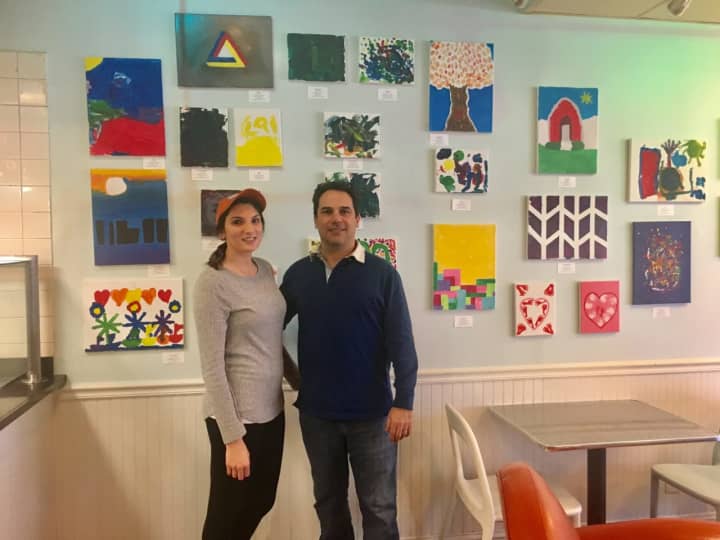 Charly Sahlia and Jazmine Damato, an employee of UCBC Darien, standing in UCBC storefront surrounded by art by Tiny Miracles foundation, which helps families with premature babies.