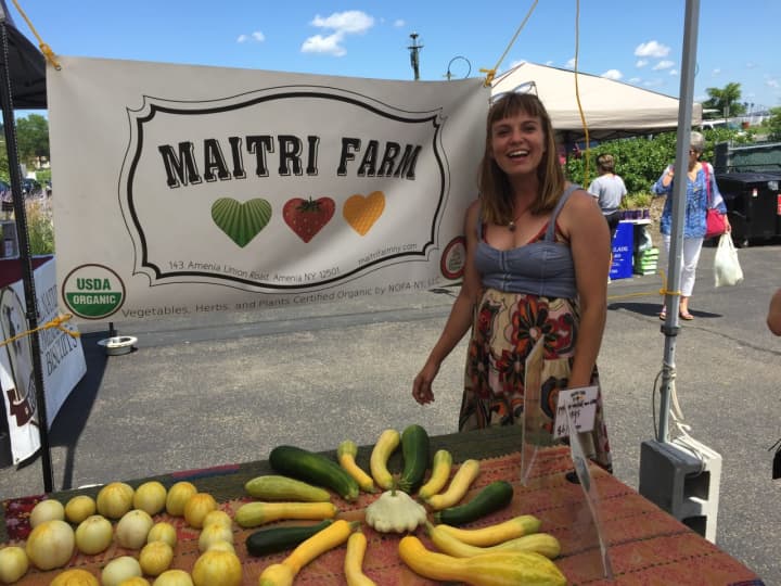 Maitri Farms vendor posing alongside some artistically placed produce.