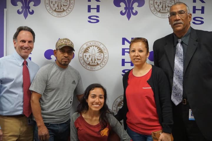 New Rochelle student-athlete Jennyfer Huerta is surrounded by her parents during the signing ceremony this week. At far right, is coach Andy Capellan. At far left is Steve Young, the district’s director of athletics.