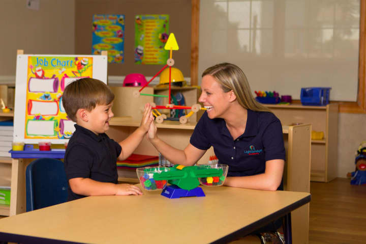 A Lightbridge Academy teacher and child share a high five.