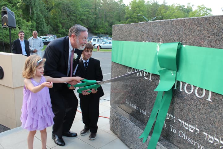 Dr. Elliot Spiegel cuts the ribbon on the stone re-naming the Solomon Schechter School in his name.
