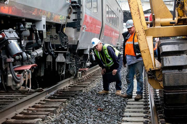 Rail workers inspect the area of the train derailment and collision along the Bridgeport-Fairfield border. 