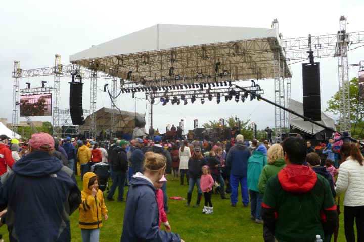 A crowd gathers around the main stage at the Greenwich Town Party despite steady rain and cold temperatures.