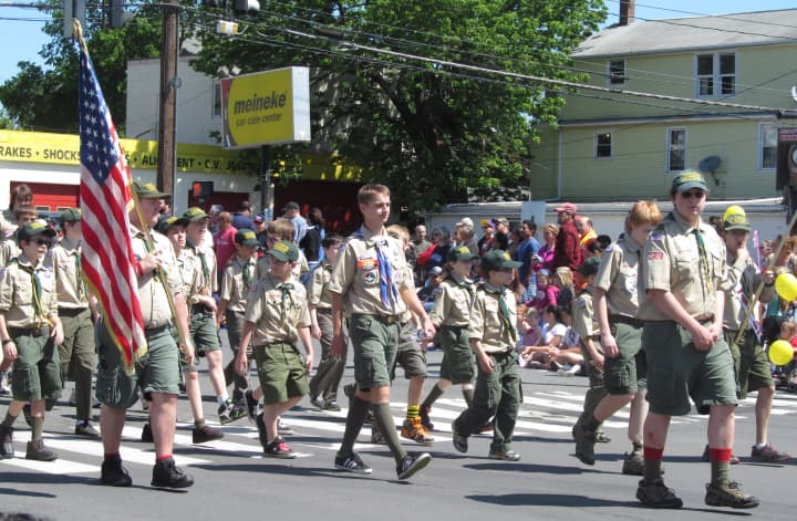 A group of Boy Scouts makes its way up a parade route. 