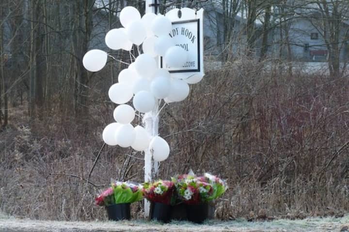 Balloons and flowers hang from the Sandy Hook School sign in Newtown only six months ago when 26 students and teachers were killed at the school.