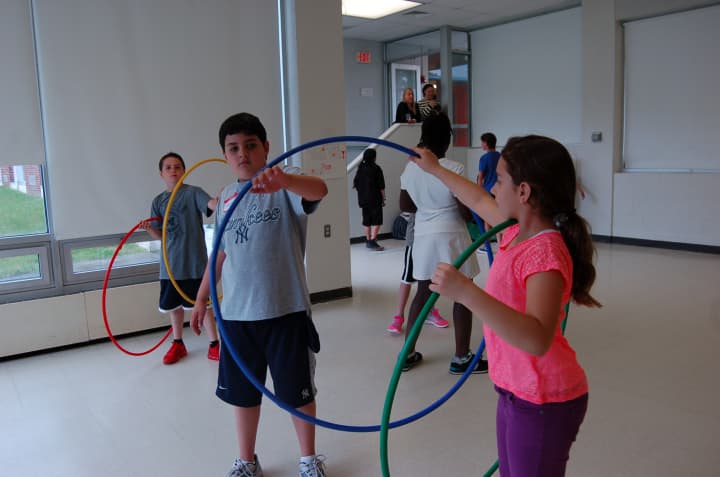 Wampus fifth-grader Ana Vataj plays hula hoops with 10-year-old Matthew Hawley, a Southern Westchester BOCES student, at the annual Special Olympics run by Wampus Elementary School in Byram Hills.