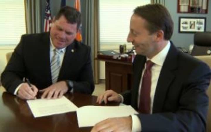 County Executive Robert P. Astorino (right) and PBA President Michael Hagan sign a tentative agreement. 