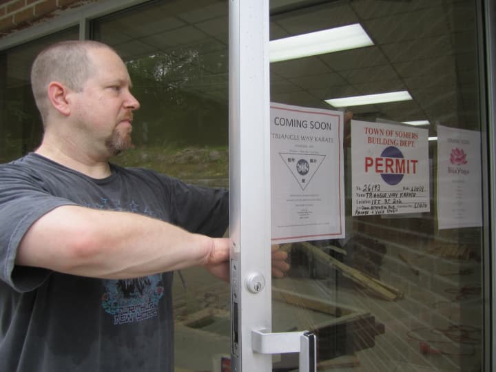 Somers resident and karate teacher Richard Norbutt places a flyer on the new karate/yoga studio opening in Somers this month. 