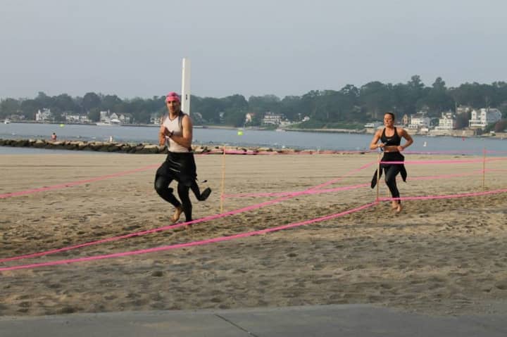Triathletes run along the beach in the transition stage from swimming to biking at the Stamford KIC It Triathlon.