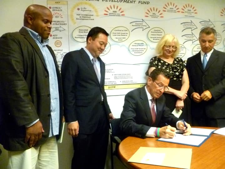 From left: Jerome Murray, State Rep. William Tong, Joan Carty, president of Housing Development Fund, and State Sen. Carlo Leone watch Gov. Dannel Malloy sign a new foreclosure bill into law. 