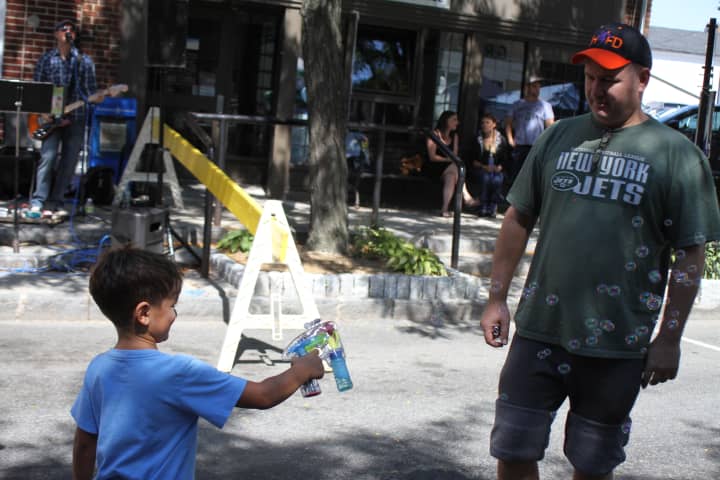 Kevin Hart, of Ardsley, blows bubbles with his son at the Sleepy Hollow Street Fair.