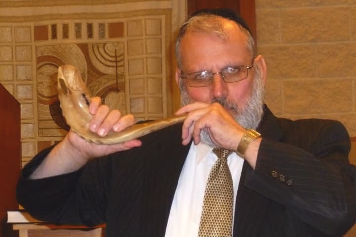 Rabbi Shmuel Greenberg blows the shofar, a ram&#x27;s horn, in the sanctuary of the Young Israel of White Plains.
