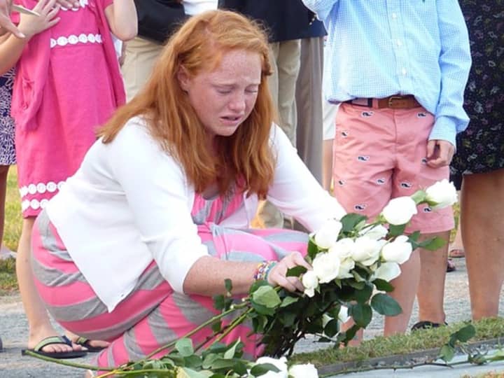 A young girl places flowers on her father&#x27;s memorial stone at the 9/11 Living Memorial at Sherwood Island State Park, in Westport.