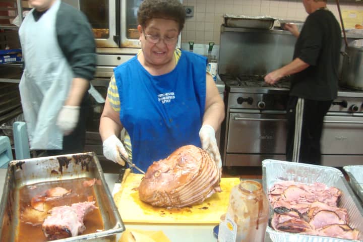 Volunteer Maria Vega slices up barbecue pork before a busy lunch at Caritas of Port Chester.