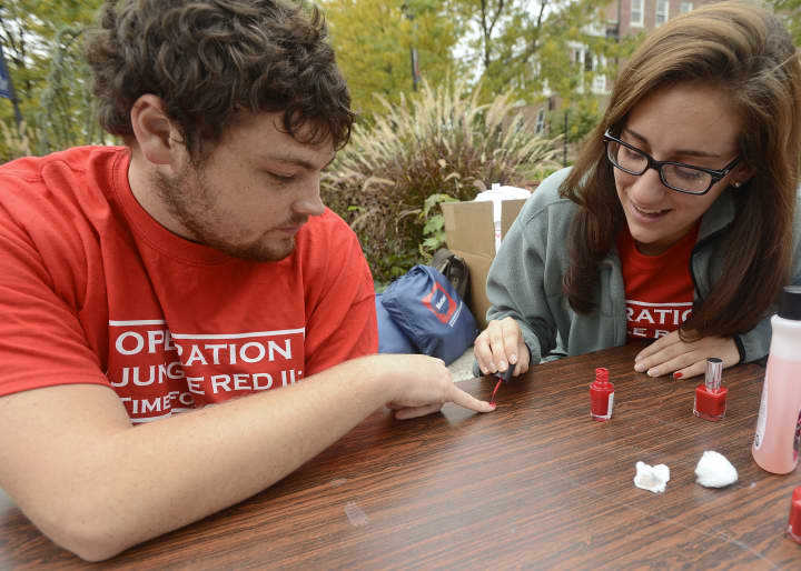 Participants in a 2012 Operation Jungle Red event at WCSU take the pledge against domestic violence and have their pinky nail painted red to affirm the commitment to non-violence.
