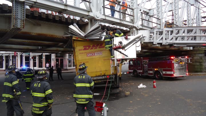 Norwalk firefighters inspect the DHL box truck stuck under a train bridge at Washington Street on Friday afternoon. 