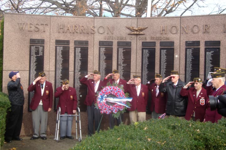 Veterans salute during Taps at the ceremony held on the West Harrison Village Green following the Veterans Day parade.
