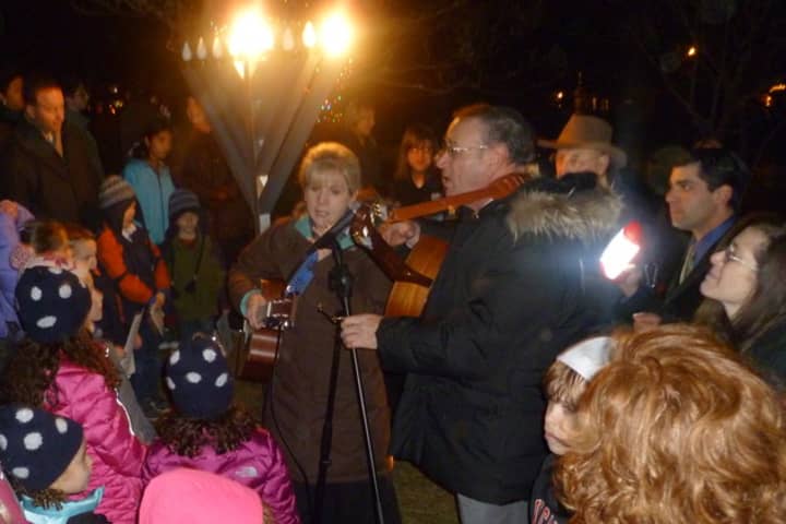 Cantor Shirah Sklar, left and Rabbi Mark Lipson of Temple Shalom in Norwalk lead the singing of songs Tuesday night at the lighting of the Menorah at God&#x27;s Acre in New Canaan. 