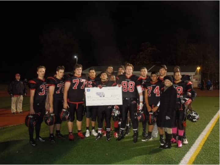 The Fairfield Warde Varsity football team presents Kelly Stewart, community events specialist with the American Cancer Society, with an $800 donation.