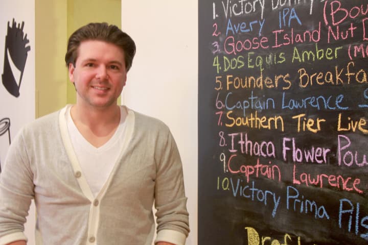 Owner Justin Tesone stands next to the craft beer list. 